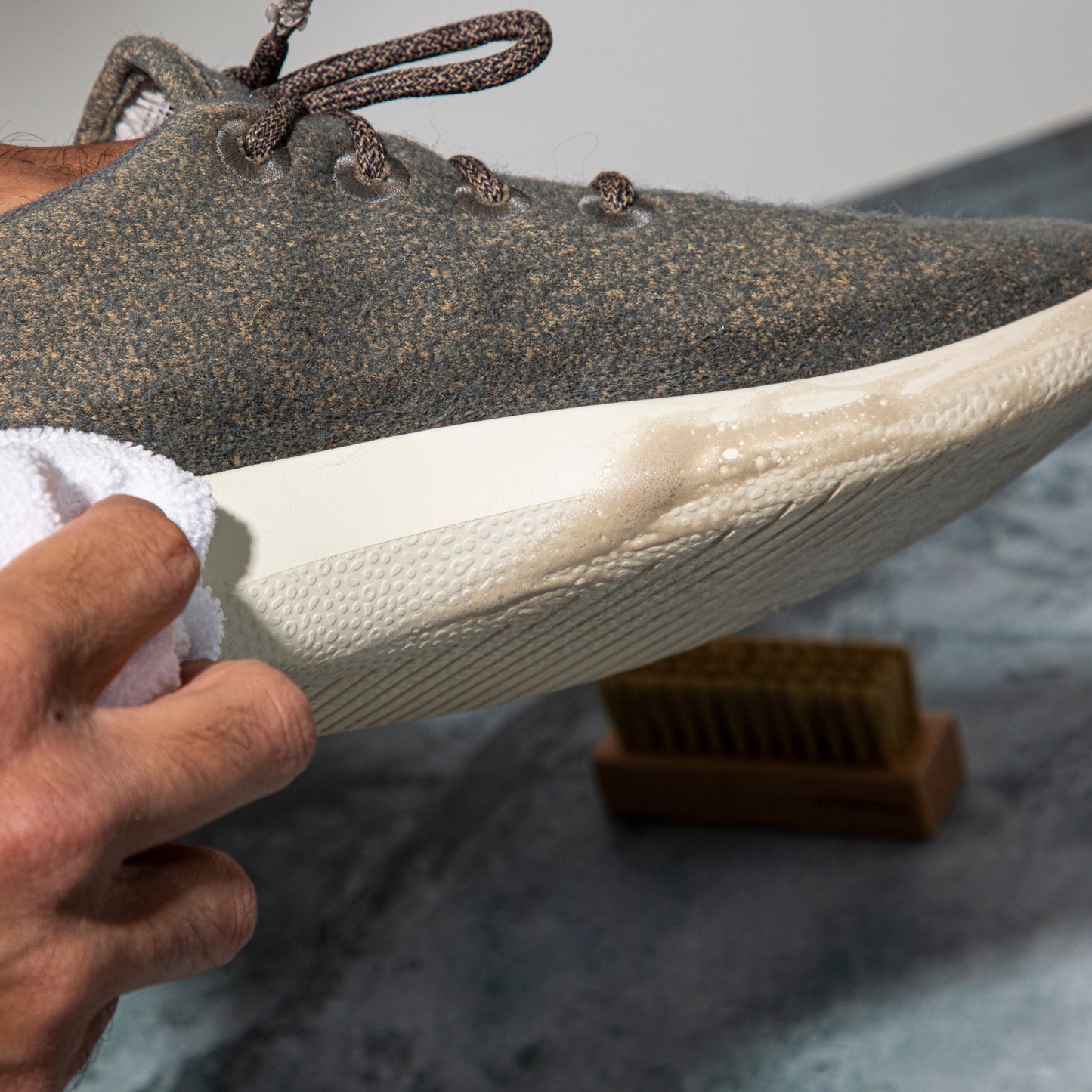 La entresuela de una zapatilla siendo limpiada con la escobilla basic